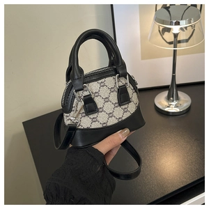Close-up of shell shaped tote bag featuring black leather trim and vintage pattern