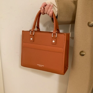 Détail d'un sac cabas élégant en cuir marron avec des boucles en métal argenté