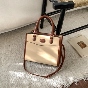 Detail shot of the two-tone patchwork tote bag on a textured rug with a fashion magazine