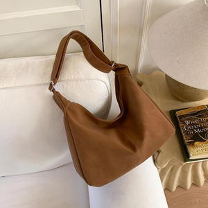 Detailed close-up of a caramel brown hobo bag on a sofa with warm interior decor