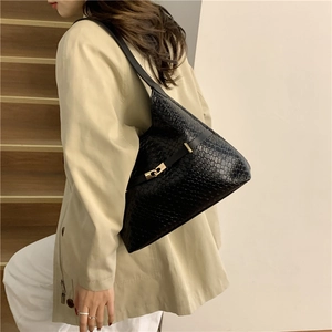 Minimalist black bucket bag with gold buckle shown from a 45-degree angle on shoulder