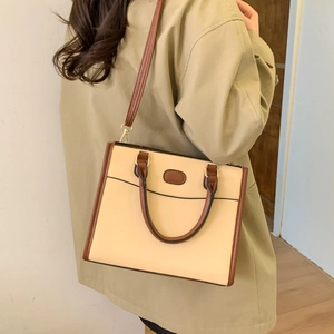 Women's beige tote bag with brown trim and shoulder strap shown in a daily lifestyle look