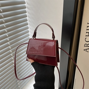 Close-up of wine red patent leather small square bag with glossy finish and top handle