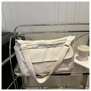 Detail of light beige waterproof nylon messenger bag with fashion label and side pocket