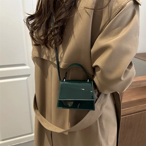 Vintage dark green mini patent leather handbag with crossbody strap on a female model