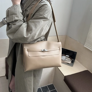 Borsa a mano minimalista in pelle beige con chiusura a scatto in argento indossata da modella