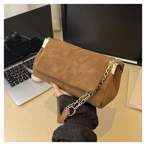 Close-up of brown suede tote bag with quilted double stitching and gold chain strap