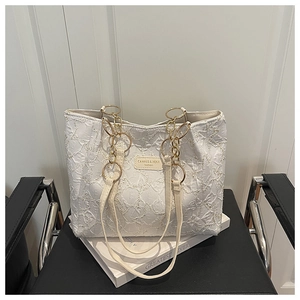 Detail of white tote bag featuring pleated texture and elegant gold chain strap design