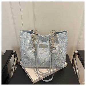 Detail of light blue tote bag with star quilted texture and gold chain strap