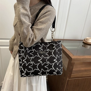 Grand sac cabas noir avec broderie d'étoiles blanches et chaîne porté par un mannequin