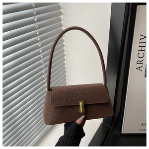 Detail of dark brown suede baguette bag with leopard embossing and gold buckle