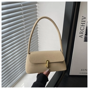 Detailed view of a beige leather baguette shoulder bag featuring a gold oval clasp closure