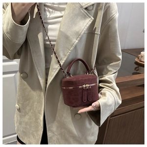 Macro detail of wine red suede crossbody bag with gold zippers and chain strap