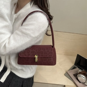 Sac baguette bordeaux rétro avec rabat léopard et fermoir doré porté par un modèle