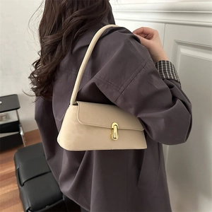 Sac sous le bras vintage en cuir beige avec fermoir doré porté par un mannequin