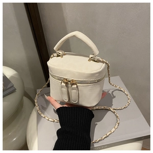 Detail of cream white quilted mini box bag with gold chain strap and dual metal zippers