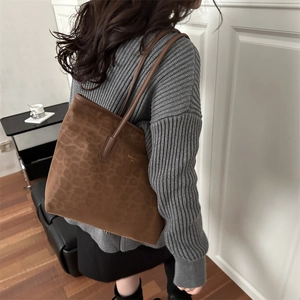 Sac cabas marron en daim imprimé léopard avec logo doré porté par un mannequin en décor chic