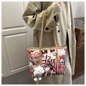 Close-up of graffiti print tote bag with plush cloud charm and brown leather straps