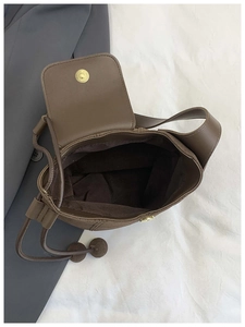 Détail intérieur d'un sac à bandoulière marron avec fermoir magnétique et pompon décoratif