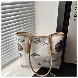 Close-up of cute astronaut illustration and faux leather trim on ivory canvas tote bag