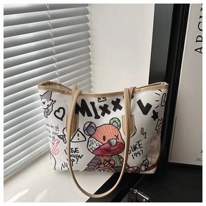 Close-up of graffiti canvas tote bag featuring colorful patches and leather straps