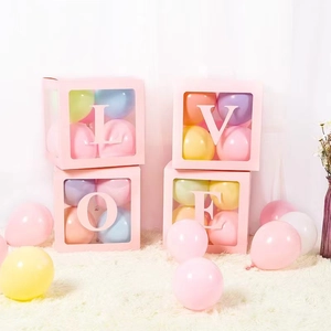 Detail of pink LOVE balloon boxes with macaron balloons on a white plush carpet