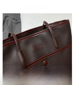 Detail der dunkelbraunen Tote Bag aus Litschileder mit Prägung und robusten Handgriffen