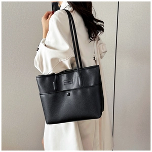Detailansicht der schwarzen Tote-Bag mit Lychee-Textur getragen mit einem hellen Trenchcoat