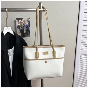 Detail der weißen Tote Bag mit Litschi-Muster, braunem Lederbesatz und Druckknopftasche