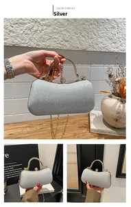 Detail of silver glitter evening clutch with metal handle and golden chain strap