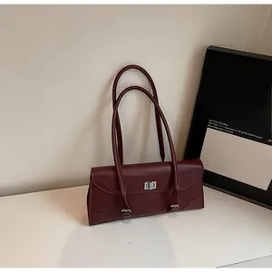 Detail of burgundy leather baguette bag with silver metal twist lock and dual shoulder straps