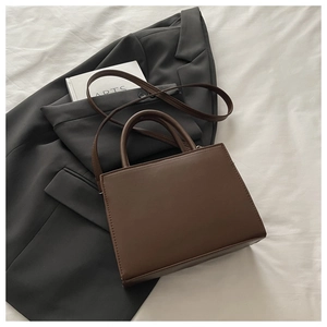 Vue de dessus d'un sac à main en cuir marron sur un blazer avec des accessoires