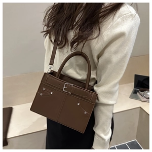 Sac bandoulière rectangulaire marron avec rivets argentés et poignée sur modèle