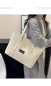 Détail d'un grand sac cabas en toile avec étiquette de mode noire sur fond blanc crème