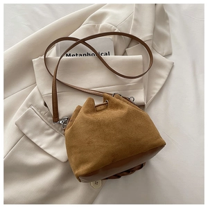 Detail of brown matte suede bucket bag with drawstring closure and silver metal hardware