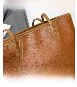 Detail of brown litchi pattern leather tote bag with reinforced stitching and logo