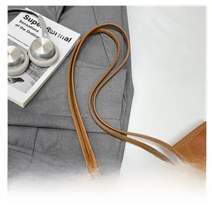 Detail of brown lychee grain leather tote bag straps with reinforced triangle stitching