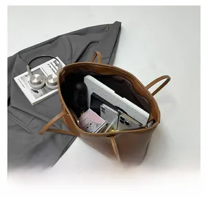 Interior capacity of the brown leather tote bag showing laptop and daily essentials