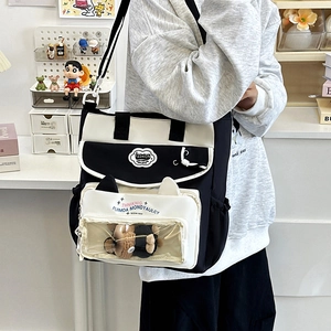 Black and white canvas tote bag with multiple pockets and a clear display window for dolls