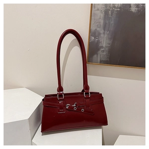 Detail of burgundy glossy leather underarm bag with metal buckles and silver eyelets