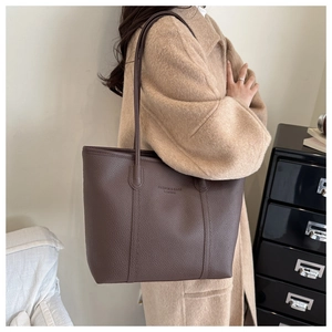 Detail of dark brown tote bag showing lychee grain leather and embossed logo