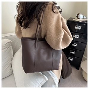 Detailed close-up of dark brown lychee leather tote bag with shoulder straps and logo