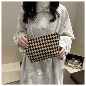 Chic quilted knit clutch bag with contrast diamond pattern held by model in trench coat