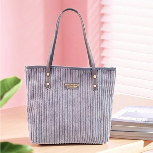 Detail of dark grey corduroy tote bag showing fabric texture and fashion logo patch