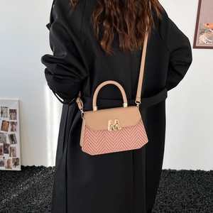 Sac à main trapèze tissé chic avec logo M doré, porté de dos sur un mannequin en manteau noir