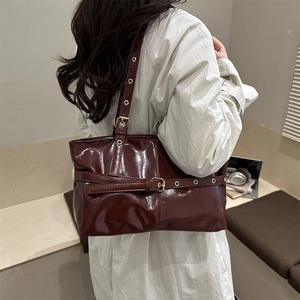 Large dark red patent leather tote bag with stylish belt buckle and metallic eyelets