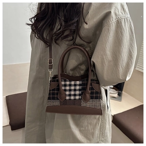 Détail d'un sac à main vintage à carreaux avec finitions en cuir brun et ornements dorés