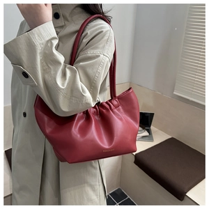 Detail of dark red cloud bag with gathered folds and elegant gold brand lettering