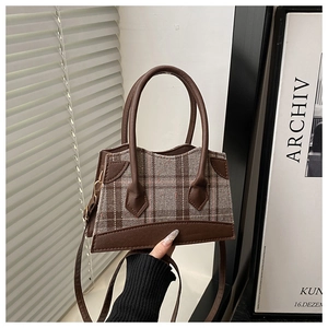 Detail van bruin leer en grijze geruite wolstiksels op de crossbodytas