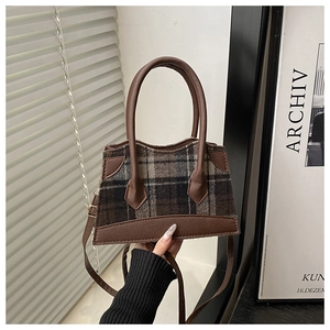 Detail van vintage geruite wollen handtas met lederen handvatten en afneembare schouderriem